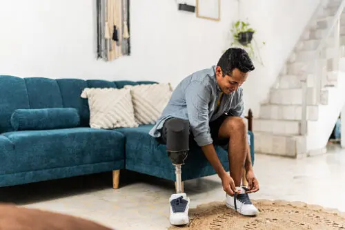 a man with a prosthetic leg sitting on a couch and tying his shoes