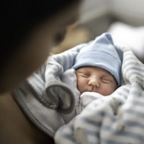 a newborn baby swaddled in a striped blanket