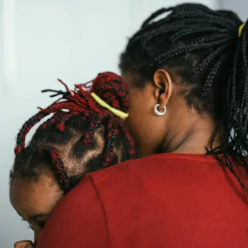 a mother with her back turned to the camera holding her child