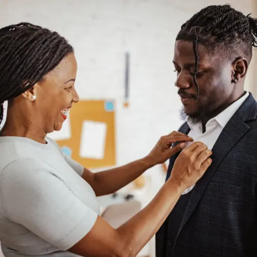 a mother carefully fixes the collar of a son’s shirt