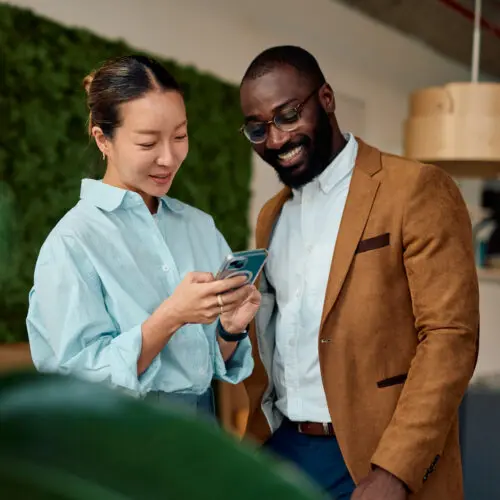 professional man and woman looking down at a smartphone and smiling