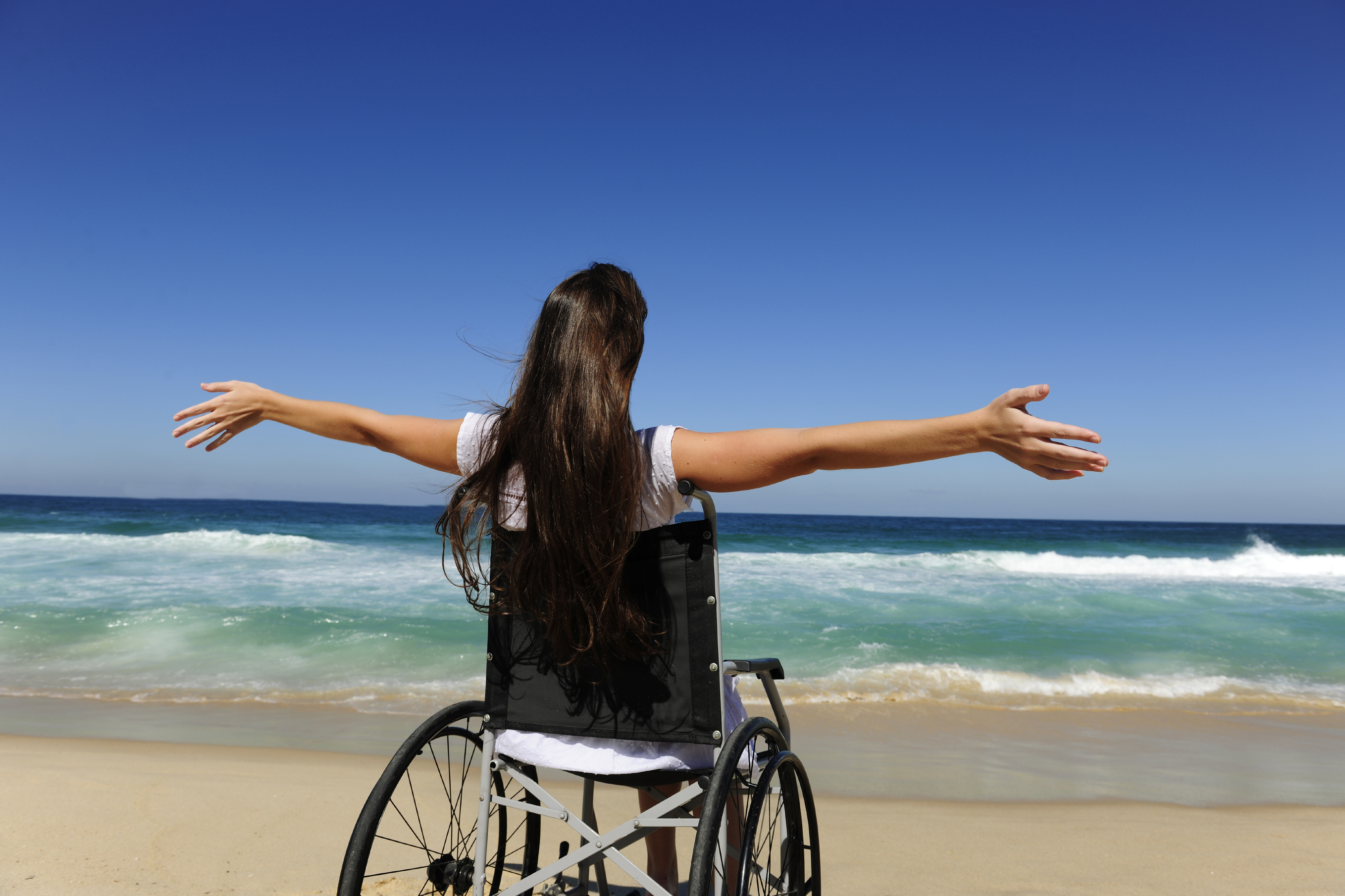 woman in wheelchair enjoying summer vacation on the beach